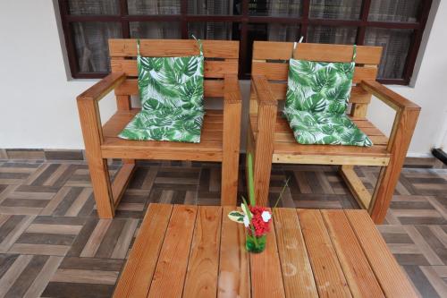 a wooden bench with green pillows and a vase of flowers at Royal Destiny Resort in Malaiyāndipattanam
