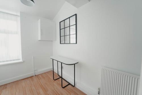 una mesa en una habitación con una pared blanca en Cheerful home close to the city and Peak District en Neepsend