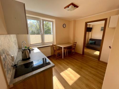 a room with a kitchen and a living room with a table at Apartament Bryza, Willa Perla 100m od morza in Gdańsk