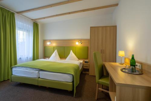 Pokój hotelowy z zielonym łóżkiem i biurkiem w obiekcie Spreewald Pension Tannenwinkel w mieście Lübbenau