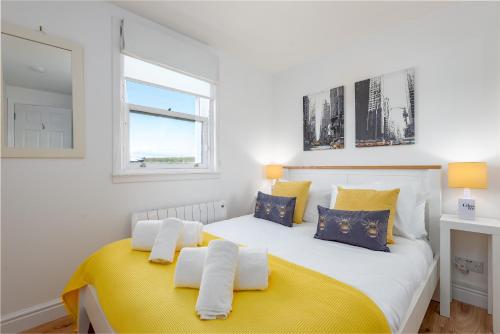 Un dormitorio con una gran cama blanca con toques amarillos en 10 Marine Park Elie - 2 Bed - 2 mins from beach, en Elie