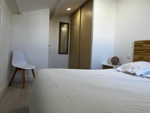 - une chambre avec un lit blanc et une chaise blanche dans l'établissement Résidence Mare Bellu Agosta plage, à Porticcio
