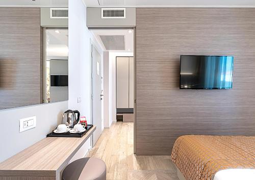 a room with a bed and a television on a wall at Hotel Savini in Bellaria-Igea Marina