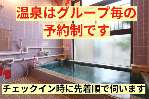 a pool of water in a bathroom with a sign above it at Tetsu no YA Guesthouse for Railfans in Fuefuki