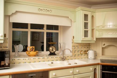 a kitchen with white cabinets and a sink at Balnagown Estates in Kildary