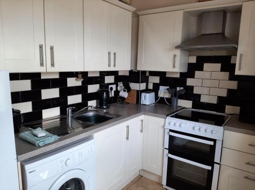 a kitchen with white cabinets and black and white tiles at Shore View in Bundoran