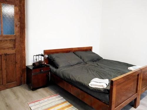 1 dormitorio con 1 cama con marco de madera y puerta en Family Apartman Szádelő - Zádiel, en Zádiel