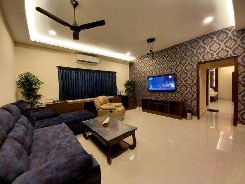 a living room with a couch and a tv at Royal Destiny Resort in Malaiyāndipattanam