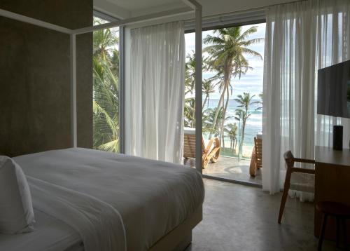 a bedroom with a bed and a view of the ocean at Harding Boutique Hotel in Ahangama