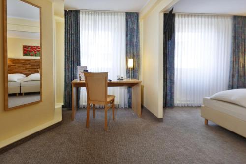 a hotel room with a desk and a bed and a mirror at City Partner Central-Hotel Wuppertal in Wuppertal