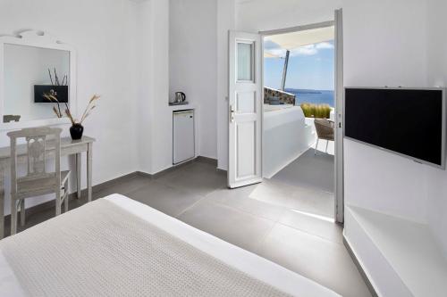 a white living room with a television and a table at Marizan Caves & Villas in Oia