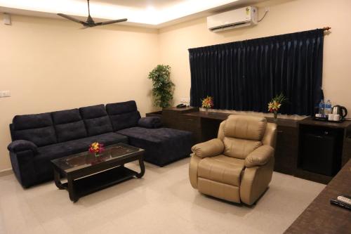 a living room with a couch and a chair at Royal Destiny Resort in Malaiyāndipattanam