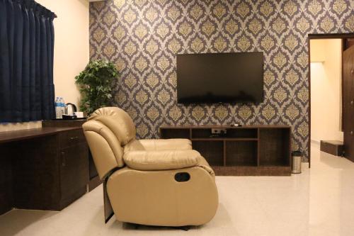a living room with a chair and a television at Royal Destiny Resort in Malaiyāndipattanam