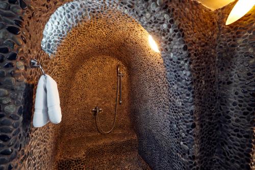 a bathroom with a shower in a stone wall at Marizan Caves & Villas in Oia