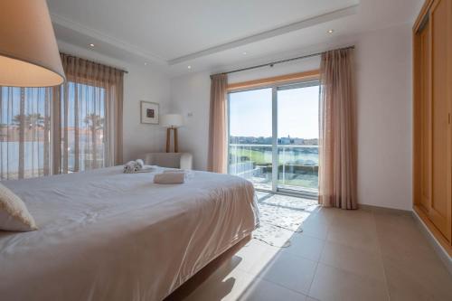 um quarto com uma cama grande e uma janela grande em Vila do Golfe Villa em Casal da Lagoa Seca