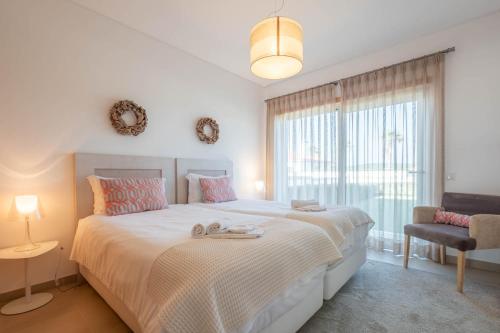a white bedroom with a large bed and a window at Vila do Golfe Villa in Casal da Lagoa Seca