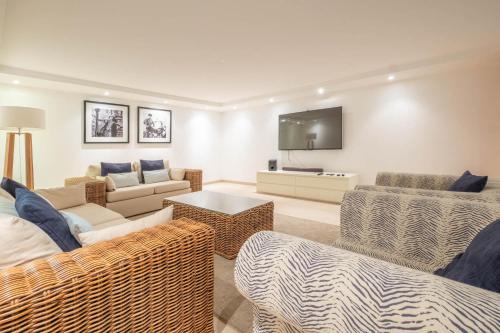 a living room with wicker furniture and a flat screen tv at Vila do Golfe Villa in Casal da Lagoa Seca