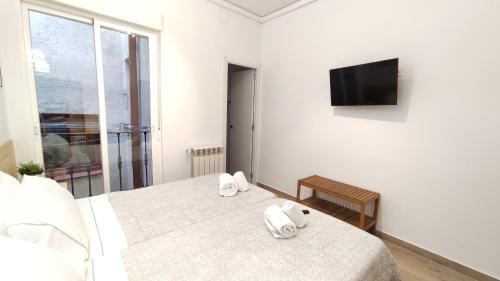a white bedroom with a bed and a flat screen tv at Hostal Aliste in Madrid
