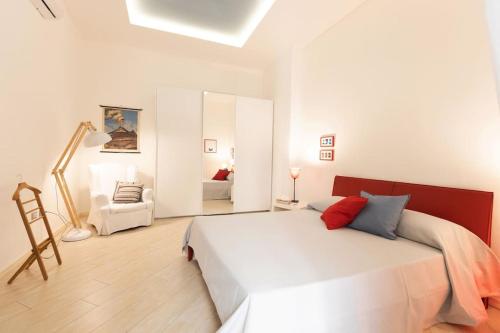 una camera con un grande letto bianco e una sedia di Casa Torrenapoli a Napoli