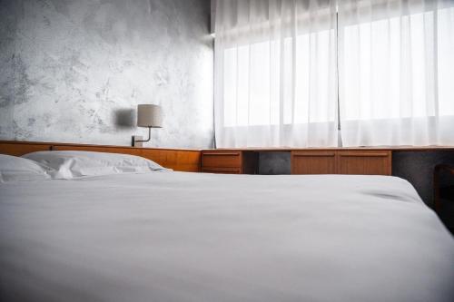 a bedroom with a white bed and a window at Hotel Valpolicella International in San Pietro in Cariano