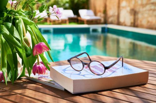 eine Brille auf einem Buch neben einem Pool in der Unterkunft Vila Branca Guesthouse - Palacete in Figueira da Foz