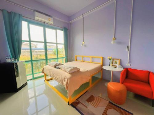 ein Schlafzimmer mit einem Bett und einem roten Stuhl in der Unterkunft Alley51 Hotel in Surat Thani