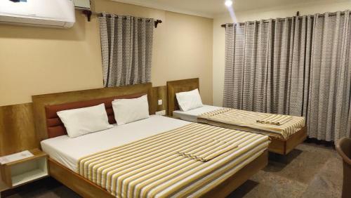 2 camas en una habitación pequeña con cortinas en Hotel Grand Stay en Tiruchchirāppalli