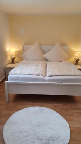 Cama blanca con almohadas blancas y alfombra blanca en Ferienwohnung im Moseltal, en Veldenz