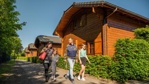 a family walking in front of a wooden house at EuroParcs De Achterhoek in Lochem