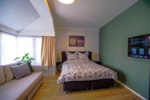 ein Schlafzimmer mit einem Bett und einem Sofa in der Unterkunft Unique Courtyard House with Sauna in Alkmaar city center in Alkmaar