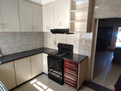 una cucina con mobili bianchi e un forno a piano cottura di Casa Línda Guest House a Newcastle