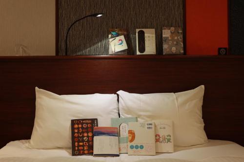 a pile of books sitting on top of a bed at BOOK HOTEL 神保町 in Tokyo