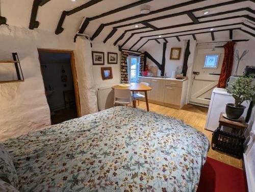 a bedroom with a large bed and a kitchen at Cobweb Cottage in Spooner Row