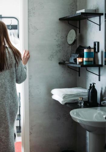a woman walking into a bathroom with a sink at Marholmen Stugby in Norrtälje