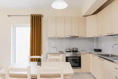 a kitchen with white cabinets and a table and chairs at CAPTAIN'S RESIDENCE in Ksamil