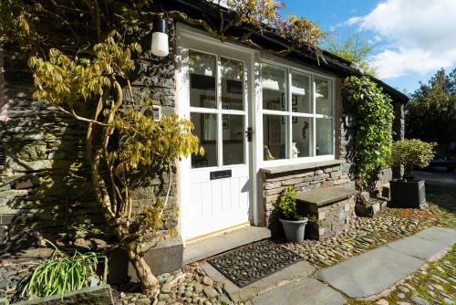 a stone cottage with a white door and windows at The Old Dairy in Ambleside