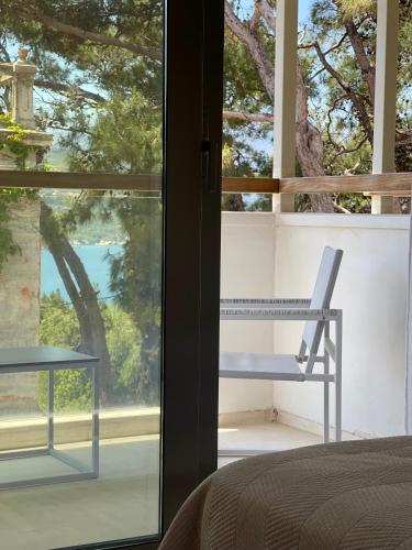 a bedroom with a window and a chair on a balcony at Ino Hotel & Suites in Samos