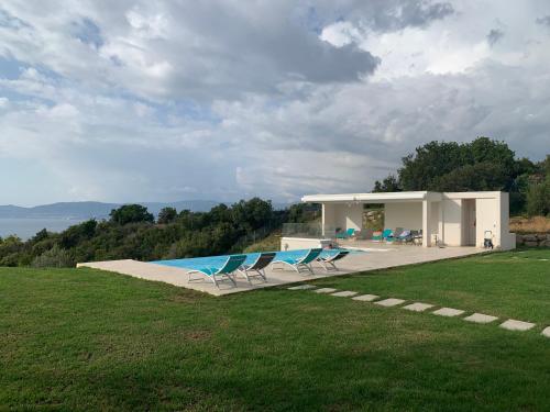 une maison avec une piscine et deux chaises dans l'établissement CORSE HOLISTIKA - Rez-de-jardin avec vue mer exceptionnelle et piscine magnifique, à Pietrosella