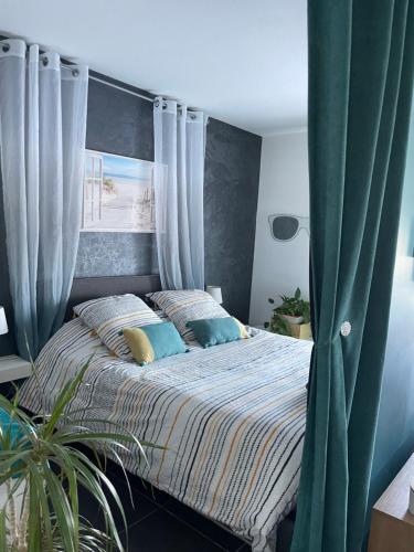 フュリアニにあるAppartement Cosy et spacieux, avec balcon et vue sur la merのベッドルーム1室(青いカーテン付きの大型ベッド1台付)