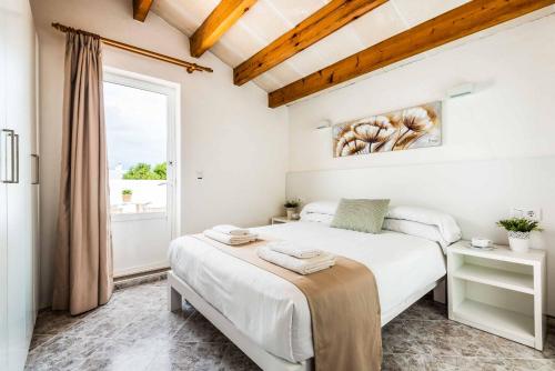 a white bedroom with a bed and a window at Villa Raquel Blanes in Cala en Forcat