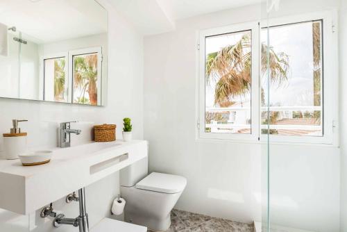 a white bathroom with a toilet and a sink at Villa Raquel Blanes in Cala en Forcat
