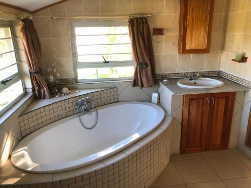 a bathroom with a tub and a sink at Bee’s Knees Cottage in Winterton