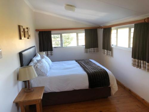 a bedroom with a bed and two windows at Bee’s Knees Cottage in Winterton