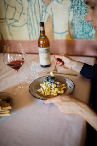 a woman sitting at a table with a plate of food and a wine glass at Cà del Re in Verduno