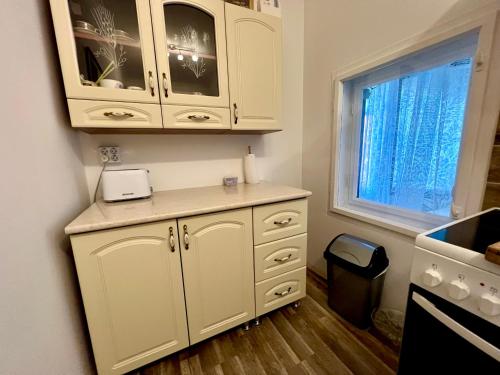 a kitchen with white cabinets and a window at Francia Ház in Balatonföldvár