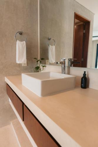 a bathroom with a white sink and a mirror at Suites at TreeTops Tulum in Tulum