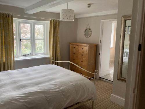 a bedroom with a bed and a dresser and windows at The Garden Cottage in Stroud