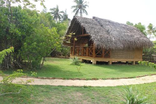 a small hut with a straw roof on a yard at Ganesh Garden Beach Cabanas in Tangalle