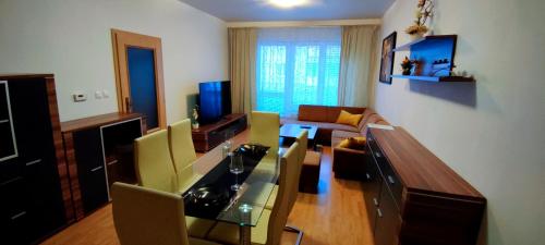a living room with a glass table and yellow chairs at 2 izbový byt 60m2 v centre na Bakossovej, 24h self checkin in Banská Bystrica