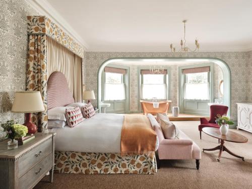 a bedroom with a large bed and a pink chair at The Retreat, Elcot Park in Newbury